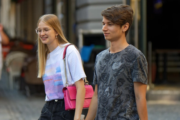 A man and a woman walking side by side on a path, engaged in conversation.